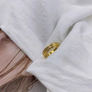 Polished gold multi-layer textured ring set in wide irregular design on white fabric