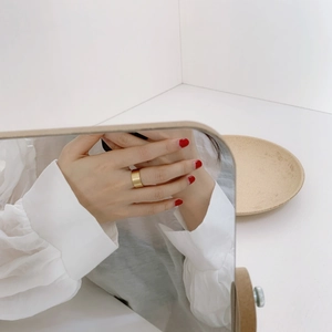 Mirror reflection showing a wide matte gold brushed finish ring on a finger