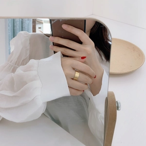 Close-up of wide gold ring with brushed metal texture and minimalist design on model