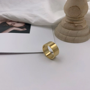 Macro detail of wide gold minimalist ring featuring a fine brushed metal texture finish