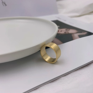 Minimalist wide band ring with golden brushed matte finish on white ceramic edge
