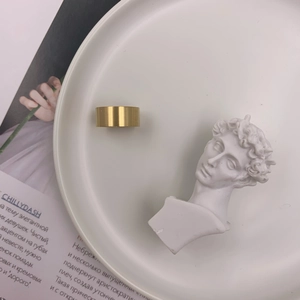 Close-up of golden wide brushed metal ring on a minimalist artistic background