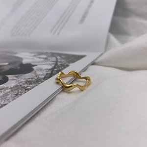 Minimalist gold wave ring featuring irregular curved design on a soft white background