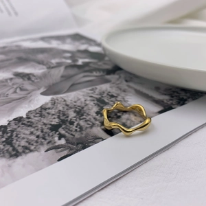 Golden wavy ring displayed on a minimalist magazine edge with elegant lighting