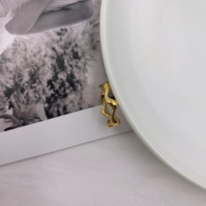 Elegant gold undulating wave ring with minimalist polished finish on a white porcelain tray