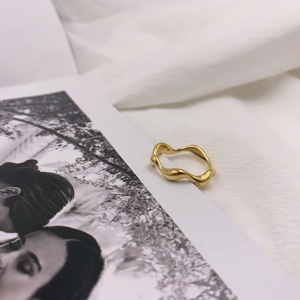 Detailed view of a gold minimalist wave ring displayed on a black and white card