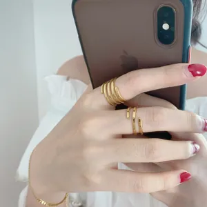 Detail of multi-layer spiral gold ring and minimalist double-line open band on fingers