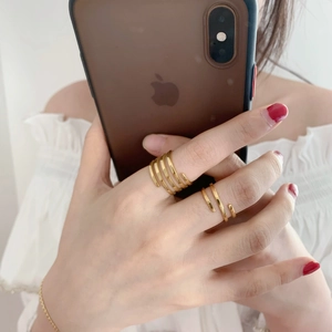 Detail of adjustable gold layered spiral rings styled in a casual lifestyle mirror selfie