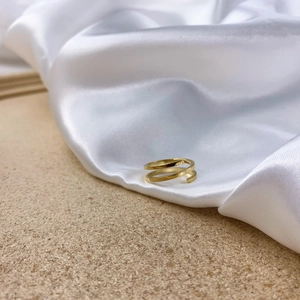 Detail view of a multi-layer golden spiral open ring on silk with cork background