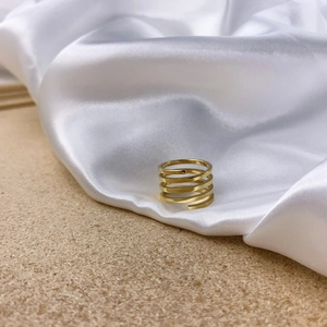 Detailed close-up of a gold multi-layer spiral minimalist ring on white silk background