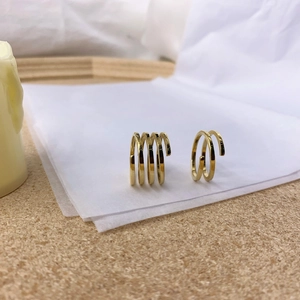 Detail view of multi-layer spiral gold earrings on a clean minimalist aesthetic background