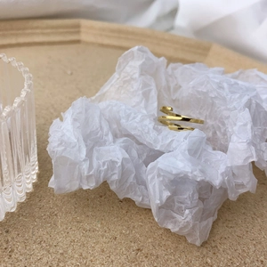 Close-up of golden multi-layer spiral ring on elegant white pleated paper display