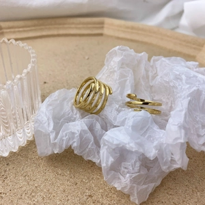 Modern gold multi-layer spiral rings with matte and polished finishes on wooden tray