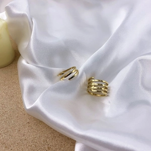 Minimalist gold multi-layer spiral ring set on white satin with decorative candle