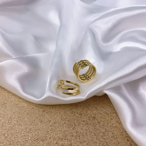 Minimalist gold spiral multi-layer ring set on white silk and wood texture background