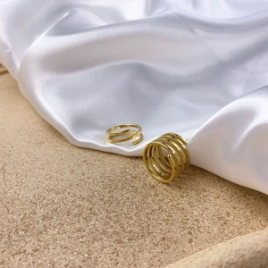 Detail of stacked gold multi-layer spiral rings on white silk and cork surface