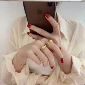 Détail de bagues dôme croissant dorées et d'un bracelet délicat sur le mannequin