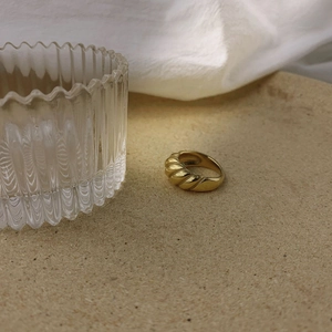 Gros plan d'une bague dôme dorée style croissant sur pierre avec un éclairage naturel