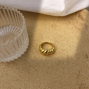 Gros plan sur une bague croissant dorée à texture torsadée sur fond liège