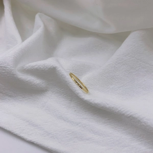 Minimalist 18K gold plated ultra-thin stackable ring on white fabric background
