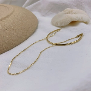 Detail of 18K gold plated minimalist chain bracelet with a polished metal bar on a white fabric