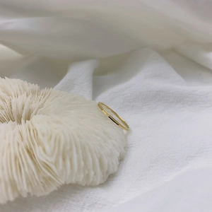 Close-up of minimalist 18K gold plated thin ring on white coral with macro details
