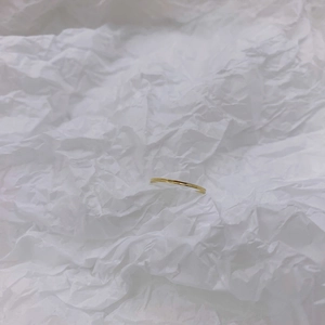 Detail of slim 18K gold plated minimalist stacking ring on white textured paper
