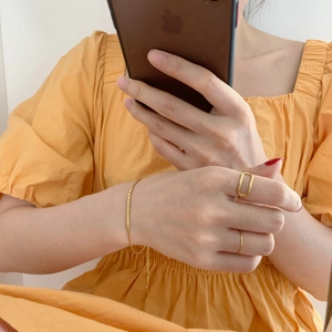 Gros plan d'une bague géométrique dorée et d'un bracelet à perles avec robe jaune