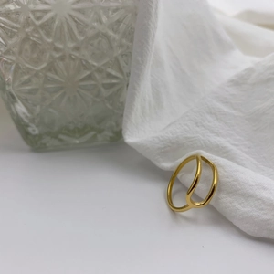 Detailed view of minimalist gold double-layered titanium steel rings on white fabric background