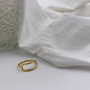 Macro shot of minimalist gold hollow geometric ring on white fabric with glass texture