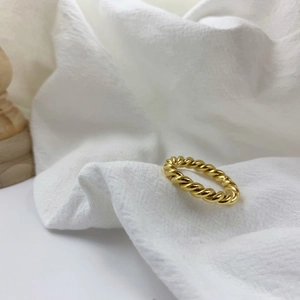 Minimalist gold plated titanium steel croissant twist ring on white fabric background