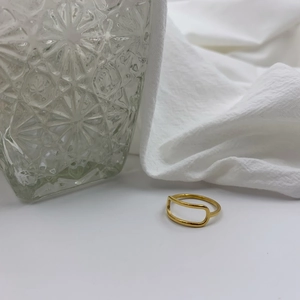 Detail of hollow geometric gold-plated titanium steel ring on white textured fabric