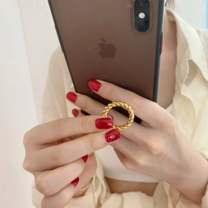 Detailed view of a gold-plated twisted rope ring on a finger with a modern metallic finish