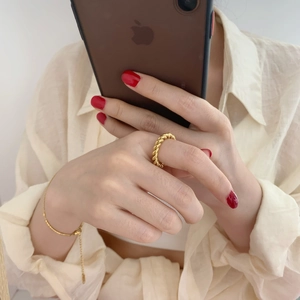 Detailed view of chunky twisted rope ring and gold chain bracelet on model's hand