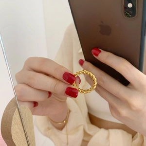 Detailed close-up of a gold braided rope ring worn on finger with a mirrored reflection