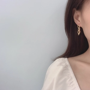 Detail view of chunky gold chain link earrings worn by a model in a minimalist style
