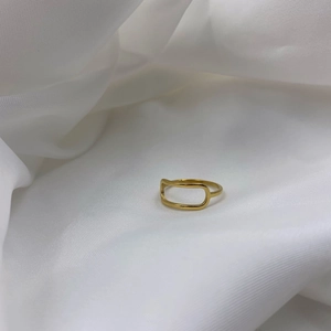 Detailed view of an adjustable gold geometric ring on a soft white silk background