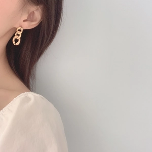 Close-up of golden metallic triple-link chain earrings worn on model for a minimalist look