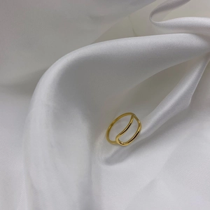 Minimalist double-layered gold geometric ring displayed on elegant white silk fabric