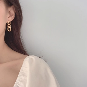 Minimalist gold chain link earrings with polished finish worn by a model on light background