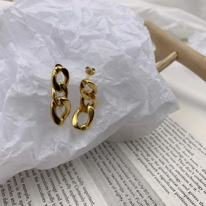 Macro view of gold chunky chain earrings on book background with polished finish
