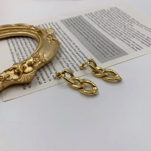 Macro detail of chunky gold chain drop earrings with interlocking oval links
