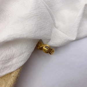 Bague chaîne dorée de style industriel présentée sur un tissu en lin blanc texturé