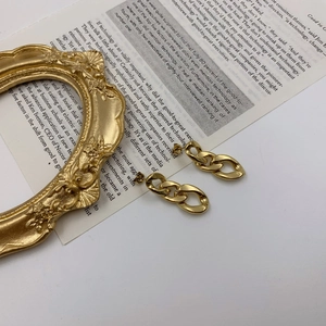 Macro view of gold chain link earrings with polished finish on a vintage background