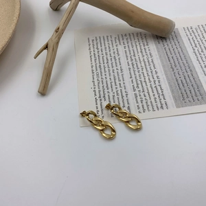 Minimalist gold chain link earrings in retro Cuban style on a vintage paper background