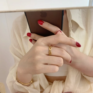 Vue rapprochée d'une bague chaîne dorée minimaliste portée au doigt au fini métallique