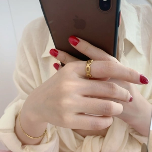 Détail d'une bague chaîne dorée vintage et d'un bracelet à billes sur une main