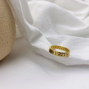 Detailed view of the golden irregular leaf pattern ring on a soft linen background