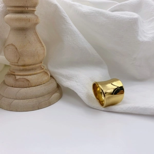 Minimalist wide gold ring with irregular concave design on textured white fabric