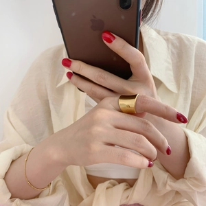 Close-up of minimalist irregular gold wide ring and delicate chain bracelet on model